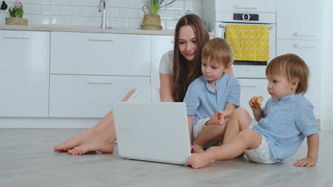 modern apartment mom and two sons sitting on the floor in the living room look at the laptop screen