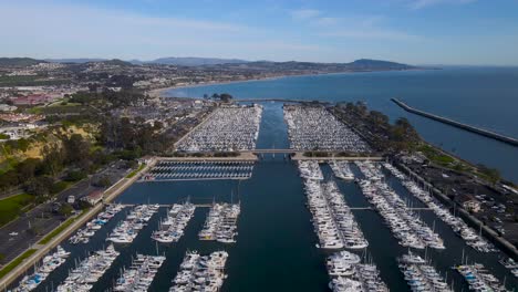 Aerial-dolly-of-coastal-town's-boat-harbor-docks-on-clear-blue-sky-day