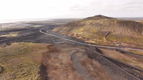 drone view over volcanic hills and winding road in iceland, unique terrain, brown rock, lava fields and open skies