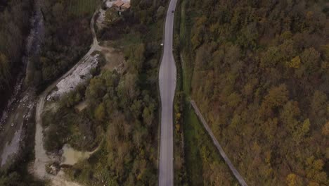 Vista-Aérea-Del-Paisaje-De-Una-Carretera-Rural-Junto-Al-Río-A-Través-Del-Bosque-De-Las-Montañas-De-Los-Apeninos,-Italia