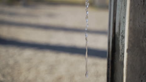 jib down of stream of water falling from wolfshead shaped faucet into small stone reservoir