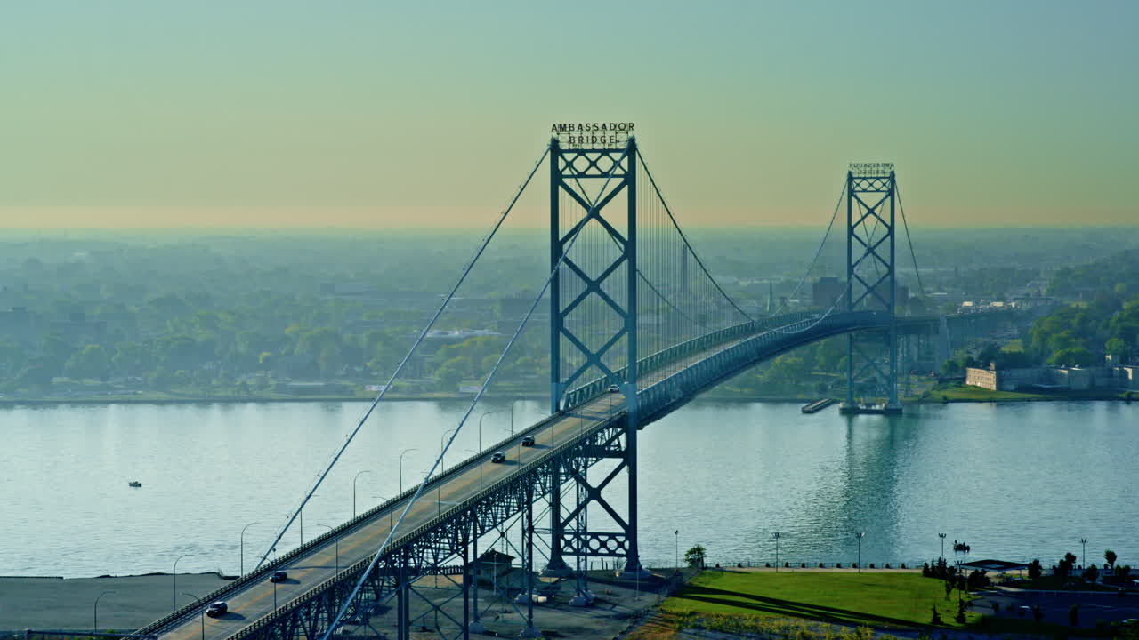Wide cinematic drone shot of the Ambassador Bridge spanning between the U.S. and Canada