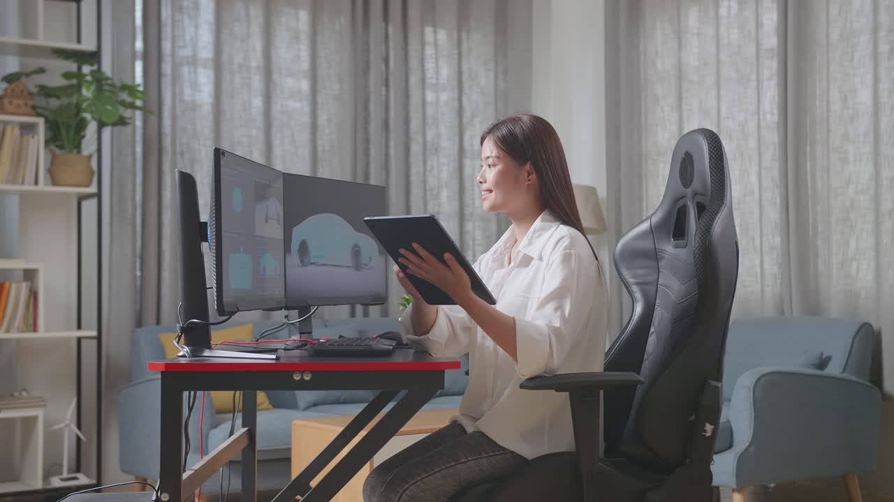 아시아 여성 자동차 디자이너가 데스크 컴퓨터에서 ev 자동차의 3d 모델을 스튜디오에서 그녀의 태블릿의 사진과 비교합니다.