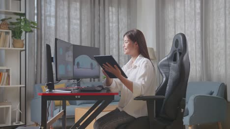 vista lateral de la diseñadora automotriz asiática comparando el modelo 3d del automóvil ev en las computadoras de escritorio con la foto en su tableta en el estudio