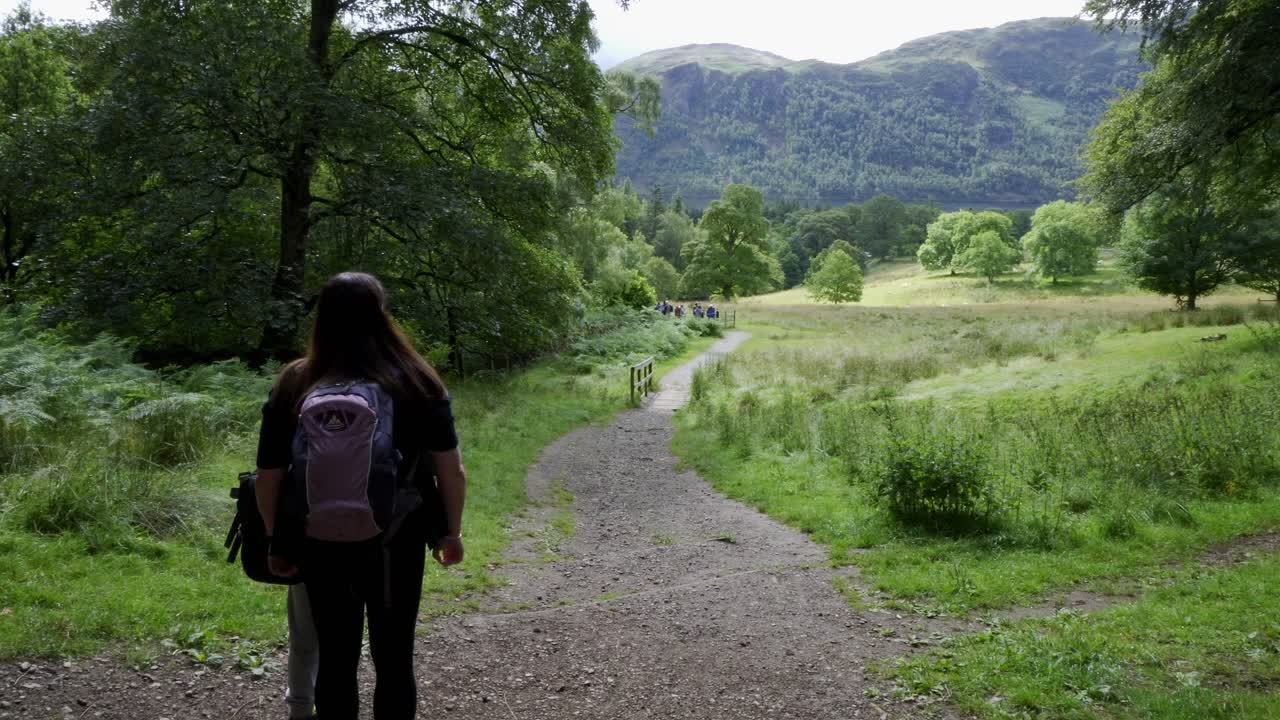mujeres excursionistas mirando la vista del campo con mochilas viajando por terreno accidentado