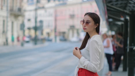 mujer esperando en una parada de tranvía en una ciudad europea