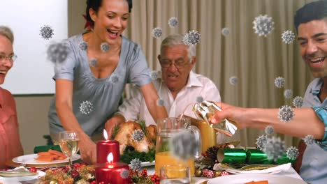 Animation-of-covid-19-cells-moving-over-multi-generation-family-sitting-at-table-for-christmas-meal-