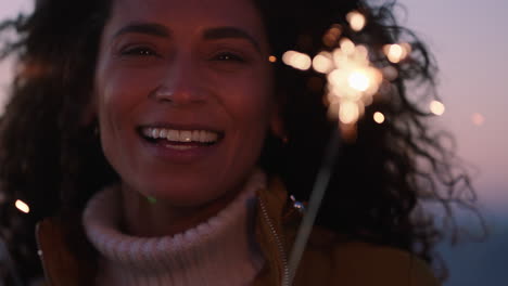 close up sparklers portrait of happy woman celebrating new years eve enjoying independence day celebration having fun on beach at sunset