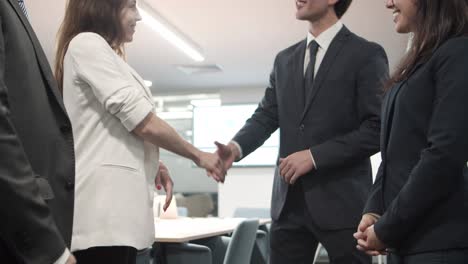 Low-angle-view-of-cheerful-workers-shaking-hands-in-office