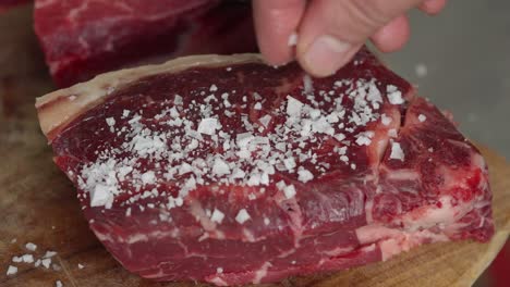 close-up of a cook salting a steak to be grilled