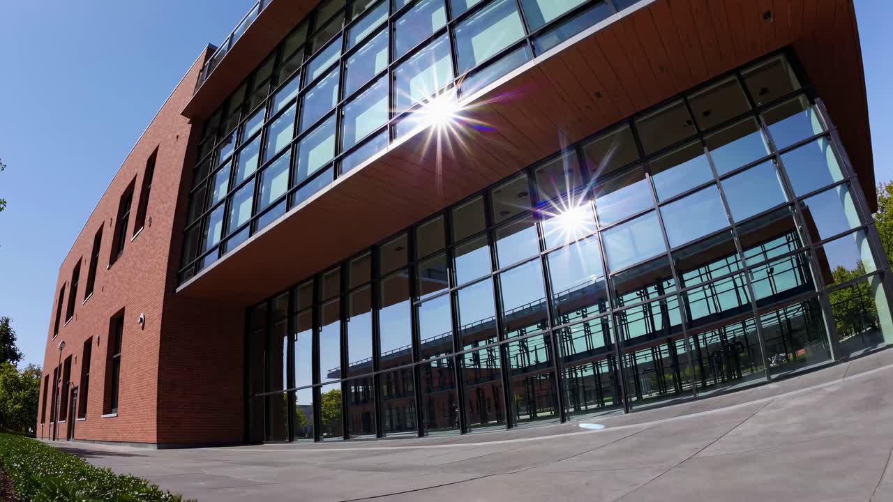 Esterno di un edificio moderno in vetro e mattoni con riflesso del sole.