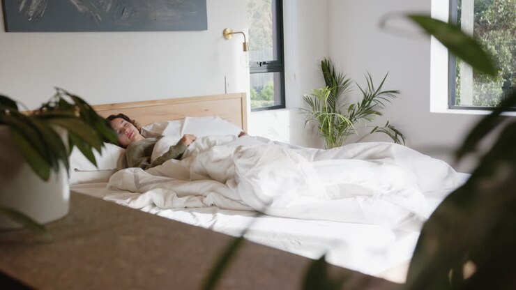 Donna si rilassa a letto, godendosi una mattinata tranquilla in una camera da letto accogliente.