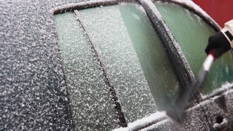 brushing and scraping snow off frozen car windows