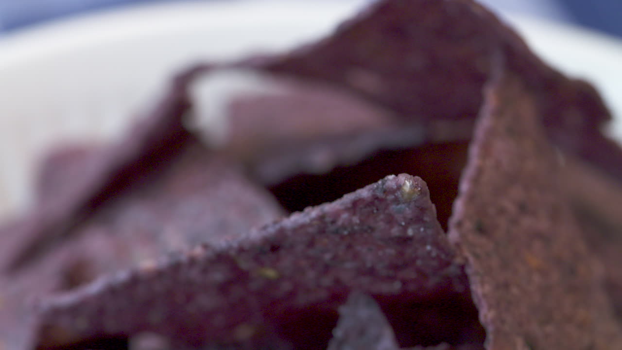 Rack focus on a bowl of blue nacho chips
