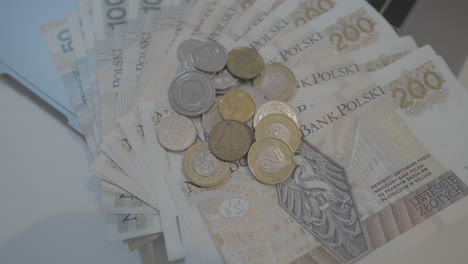 overhead close up view of various polish bank notes fanned out with coins stacked on top