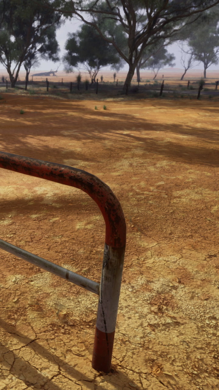 Rusty gate framing a vast dry landscape under the fading sun in rural setting