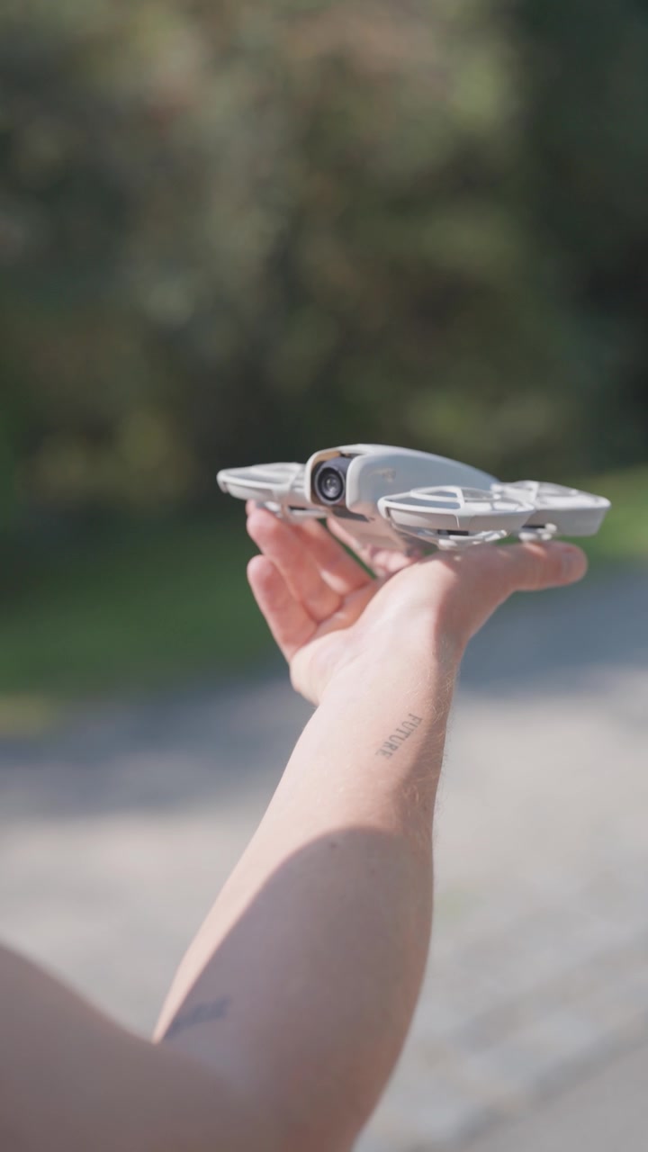 Persona che lancia e afferra un piccolo drone con le mani, sfondo esterno sfocato