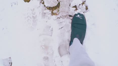 man feet in dark boots walk along clean white snow and sleek