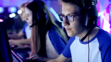 un niño jugador profesional juega en un videojuego en un torneo de deportes electrónicos o un café de internet. lleva gafas y auriculares y habla en el micrófono.