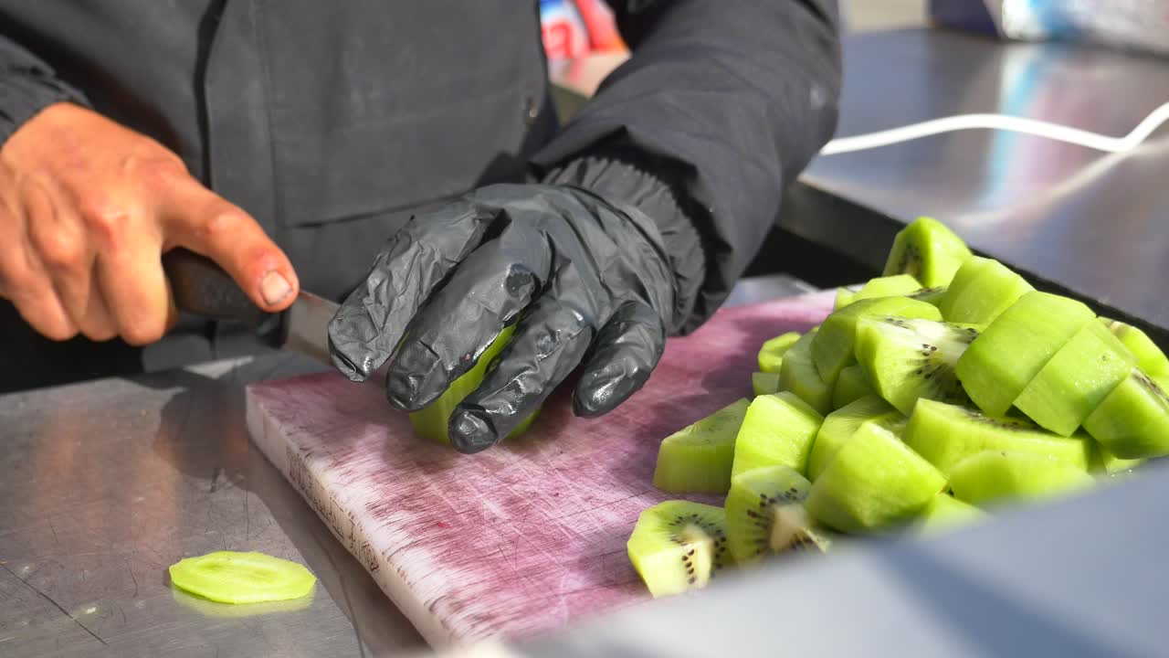 Person cutting kiwi fruit on a cutting board