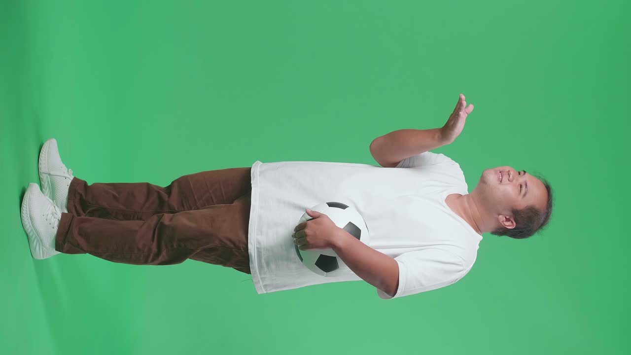 Full Body Of Asian Man With A Ball Blowing Kisses And Smiling While Cheering Soccer On Green Screen Background
