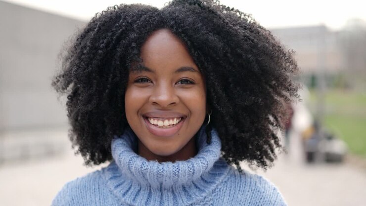 Belle jeune femme africaine souriant à la caméra en extérieur