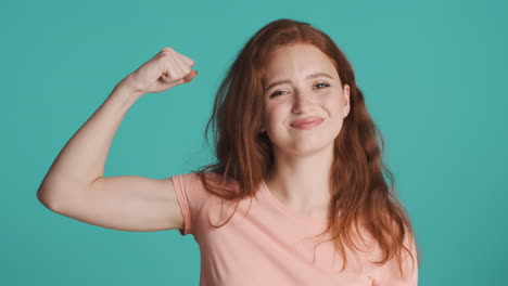 redheaded girl in front of camera on turquoise background.