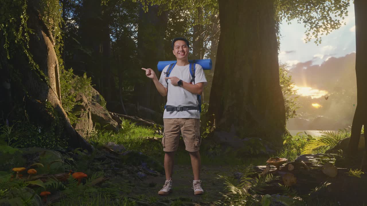 산악 배을 가진 아시아 남성 하이커의 몸이 가득 차 있으며 숲의 자연을 탐험하는 동안 웃고 을 가리키고 있습니다.