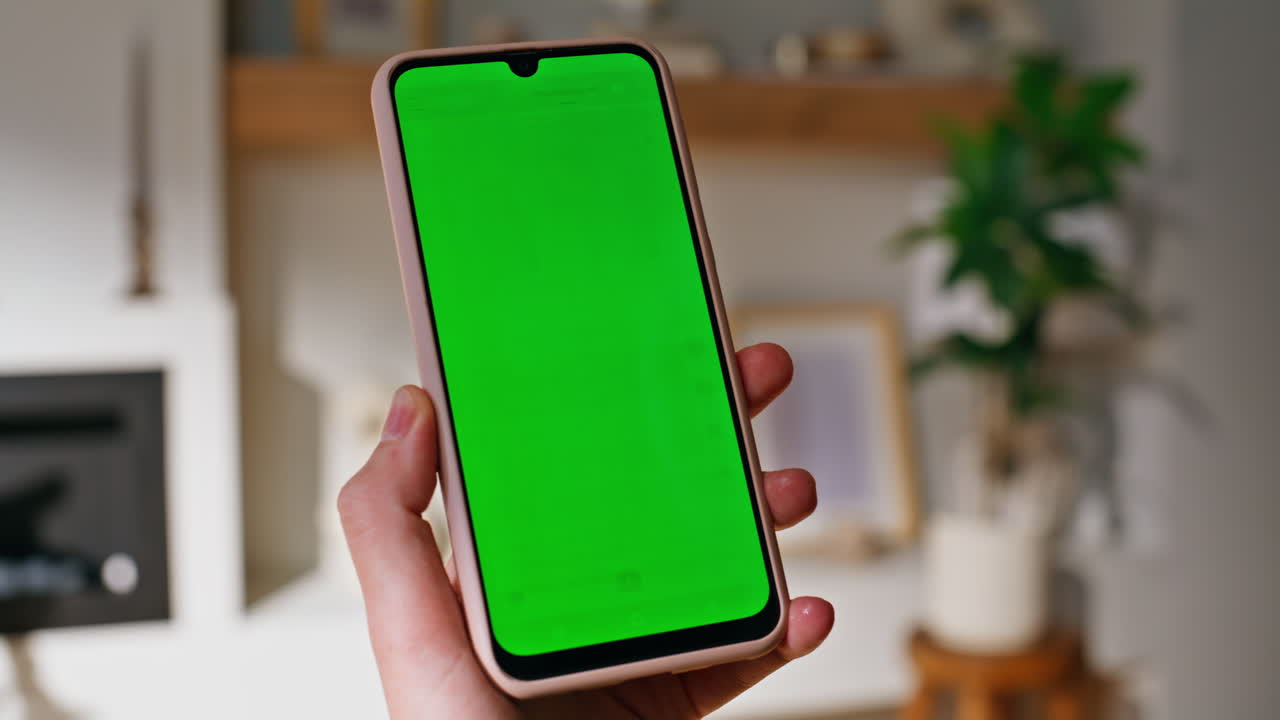 Freelancer watching chromakey mobile phone in contemporary apartment closeup