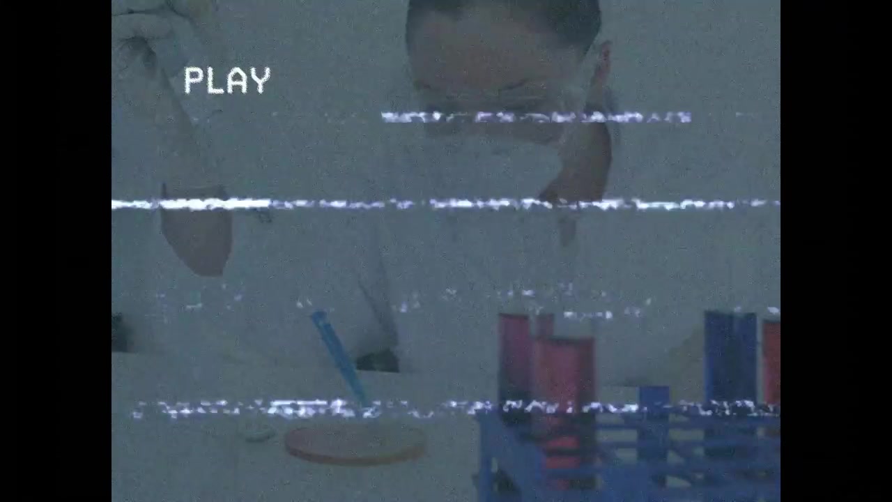 静止画で、科学者がピペットを手に取り、ペトリ皿に分注して検体を分析する様子。
