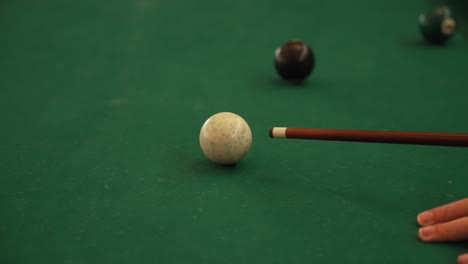 pool cue positioned behind white ball on green felt with other billiard balls in frame