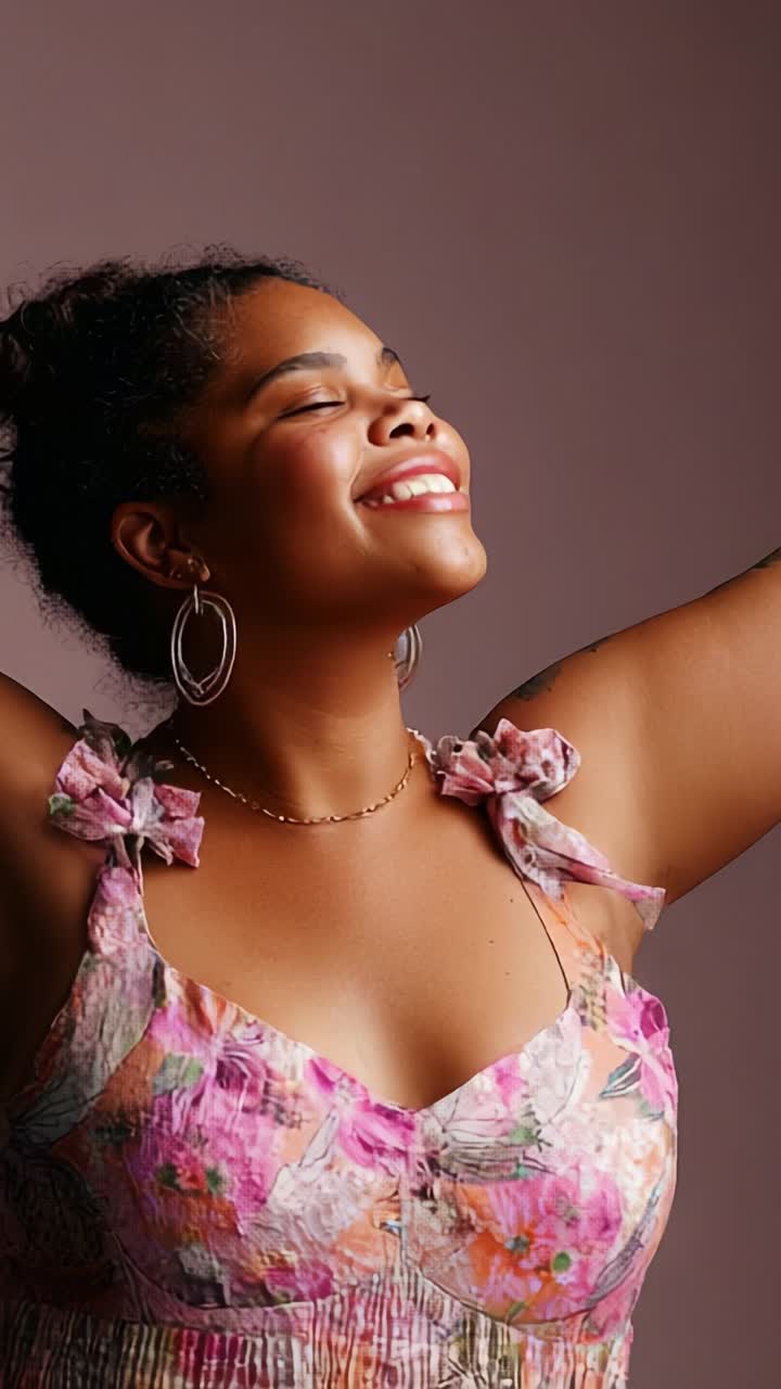 Una giovane donna radiosa che si gode il momento, mettendo in mostra bellezza e sicurezza di sé in un vivace abito a fiori, sullo sfondo di un tono morbido e caldo