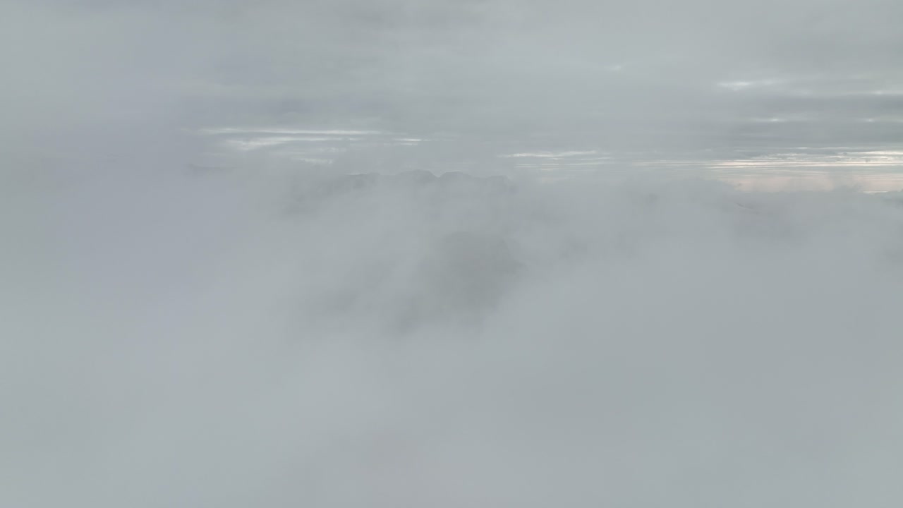 Aerial view of mountain peaks emerging through thick clouds at Hafursey, Iceland, creating a dramatic and serene scene under a cloudy sky.