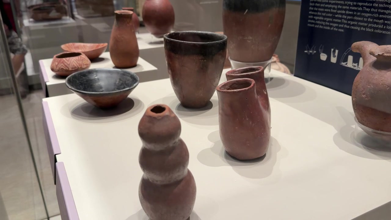 Langsamer Kameraschwenk über antike Terrakottagefäße und Tonartefakte in einer Museumsausstellung