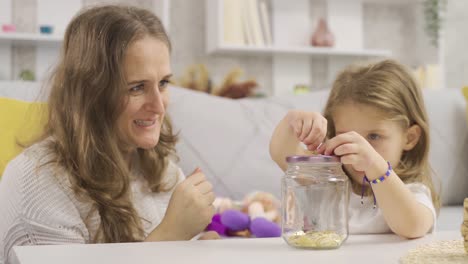 gold is being thrown into her little girl's piggy bank for her future.