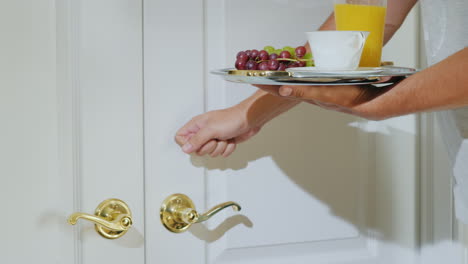 a male waiter brings breakfast on a tray to a hotel room gets a tip