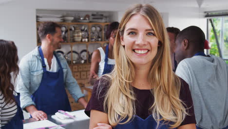 portrait of smiling woman wearing apron taking part in cookery class in kitchen
