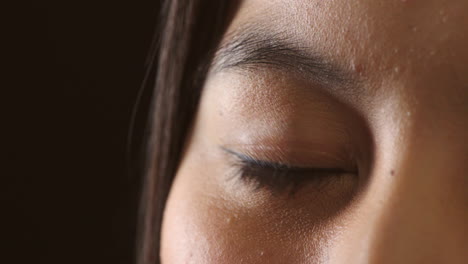 Closeup-of-a-female-eye-blinking-on-dark-studio