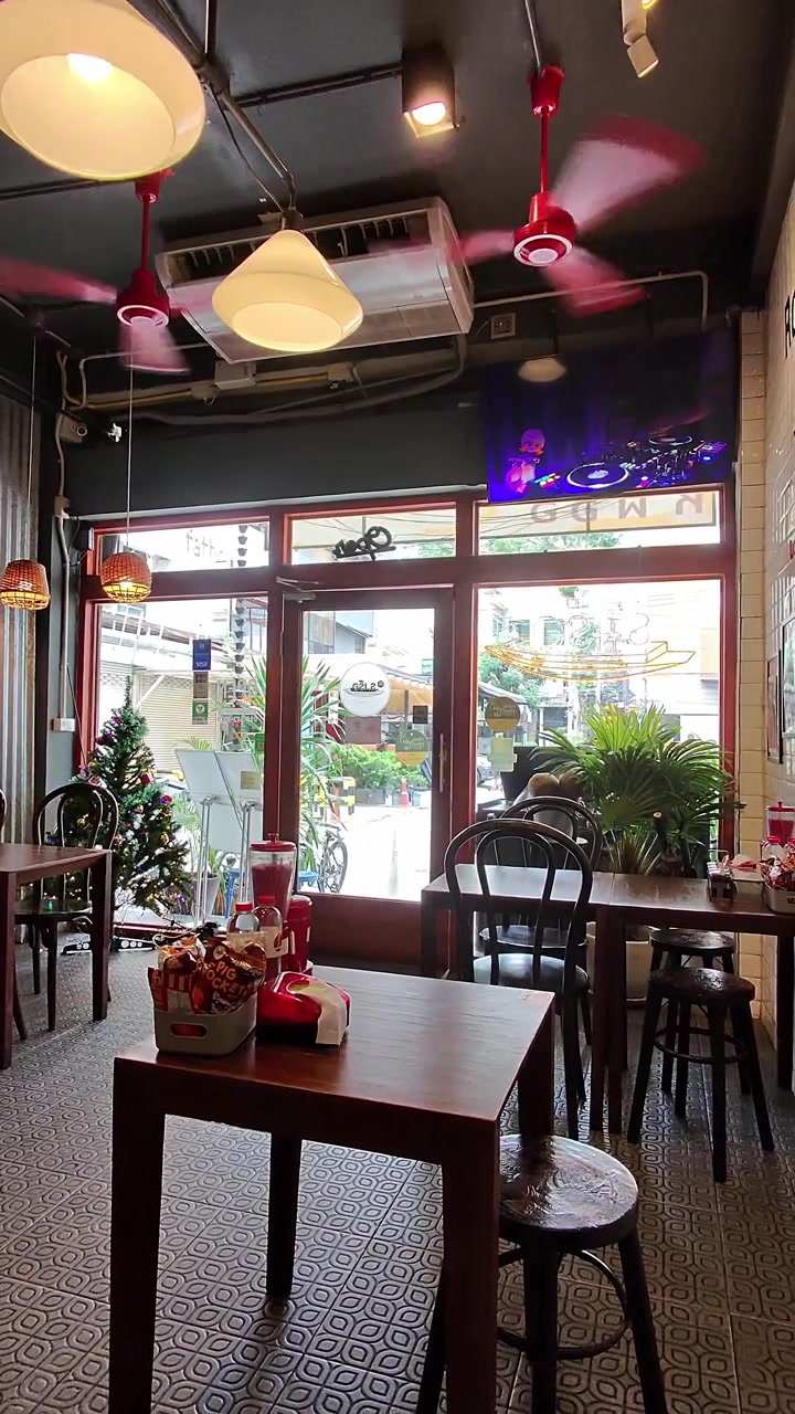 Static interior shot of bright noodle shop with spinning ceiling fans and streetfront windows