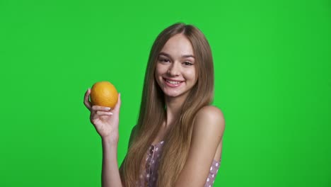 smiling girl wearing summer dress holding orange fruit