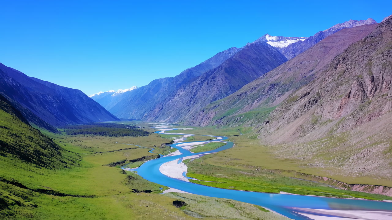 Blue River Winding Through Valley With Snowcapped Peaks, Green Meadows And Turquoise Water Curving Past Rocky