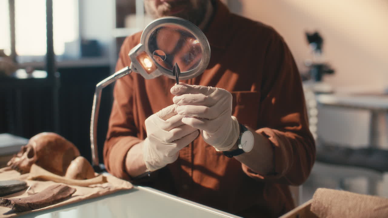 arqueólogo examinando la antigua punta de flecha bajo una lupa