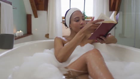 mixed race woman taking a bath and reading book