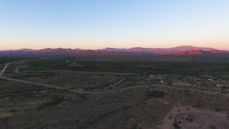 panning drone shot of arizona desert with mountains glowing pink as the sun sets near flagstaff arizona