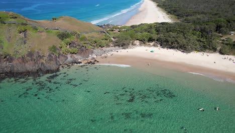 Una-Vista-Aérea-Más-Cercana-Del-Promontorio-De-Norries-Con-Turistas-Disfrutando-Del-Océano-En-La-Playa-De-Cabarita,-Tweed-Shire,-Bogangar,-Northern-Rivers,-Nueva-Gales-Del-Sur,-Australia