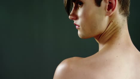 androgynous man posing against green background background