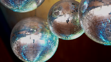Close-up-of-sparkling-disco-balls-with-blue-tints-slowly-rotating