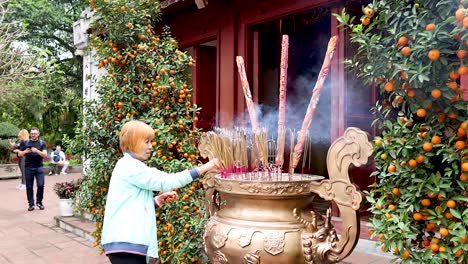 person lighting incense sticks at temple