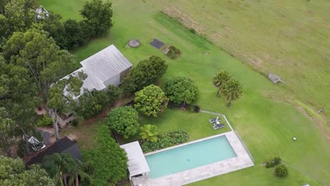 aerial footage showcasing a swimming pool surrounded by lush greenery and nearby buildings.