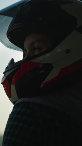 head view of a lady in a helmet, with sun light reflecting through the visor as she gazes to the right